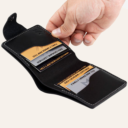 MZ Leather Craft açık siyah Buttero deri yatay cüzdan, 6 kart bölmesi ve el ile sunum. Kartlar üzerindeki profesyonel gravür metinler ve MZ logosu net. | Open black Buttero leather horizontal bifold wallet by MZ Leather Craft presented by hand with professionally engraved texts and MZ logo.