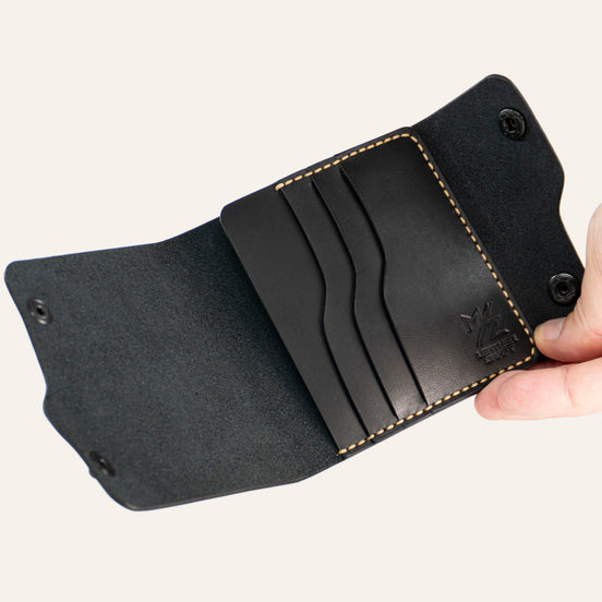 MZ Leather Craft açık dil kapaklı siyah Buttero deri cüzdan, el ile tutulan boş iç görünüm, kıvrımlı kart yuvaları ve sarı el dikişi detayları | MZ Leather Craft Tongue-Flap Wallet - Black Buttero Leather open interior view held by hand, showcasing empty curved card slots and yellow hand-stitching details
