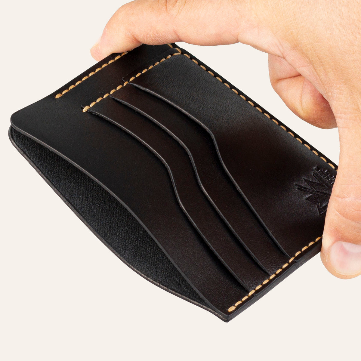 MZ Leather Craft siyah Buttero deri ters cüzdan, el ile tutulan hafif açılı boş görünüm, ana bölmeyi ve sarı saraç dikişi detaylarını gösteren açı | The Inverse Wallet - Black Buttero Leather by MZ Leather Craft, empty view held by hand at a slight angle, showcasing the main compartment and yellow saddle-stitching details