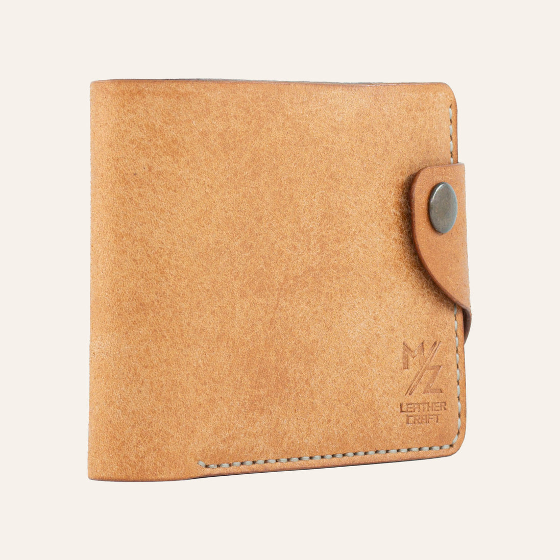 MZ Leather Craft hafif açılı natürel Pueblo deri klasik erkek cüzdanı, kapalı duruş ve kontrast açık gri el dikişi detayları | MZ Leather Craft slightly angled cognac Pueblo leather classic bifold wallet, closed position showing edge structure and light gray hand-stitching details