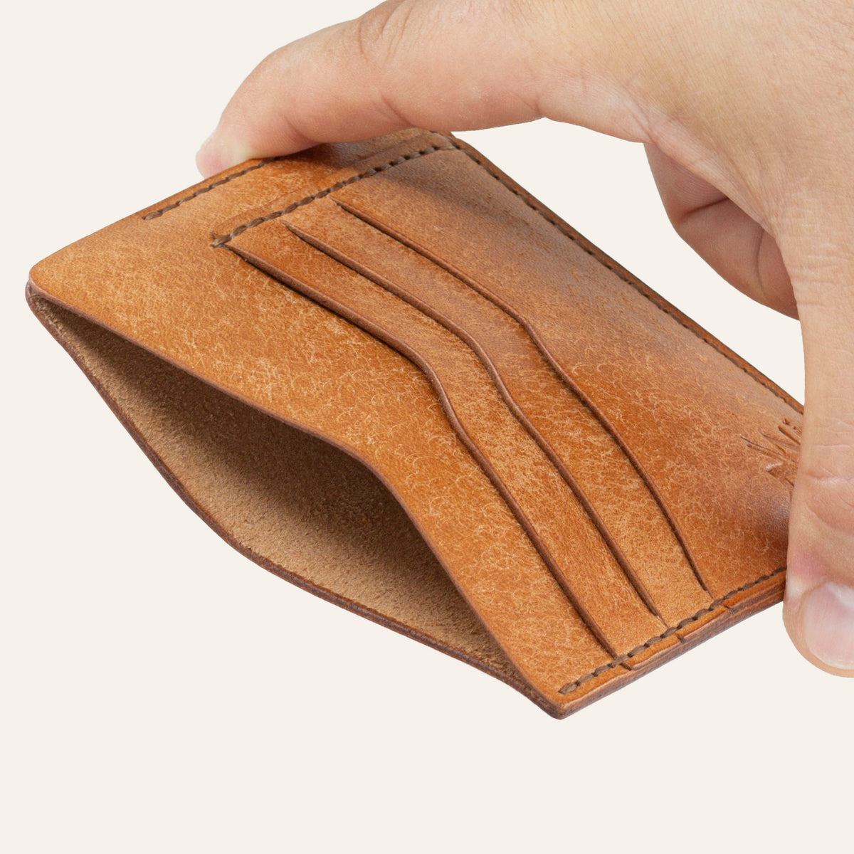 MZ Leather Craft natürel Pueblo deri ters cüzdan, el ile tutulan hafif açılı boş görünüm, ana bölmeyi ve kahverengi saraç dikişi detaylarını gösteren açı | The Inverse Wallet - Cognac Pueblo Leather by MZ Leather Craft, empty view held by hand at a slight angle, showcasing the main compartment and brown saddle-stitching details
