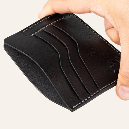 MZ Leather Craft siyah Pueblo deri ters cüzdan, el ile tutulan hafif açılı boş görünüm, ana bölmeyi ve gri saraç dikişi detaylarını gösteren açı | The Inverse Wallet - Black Pueblo Leather by MZ Leather Craft, empty view held by hand at a slight angle, showcasing the main compartment and gray saddle-stitching details