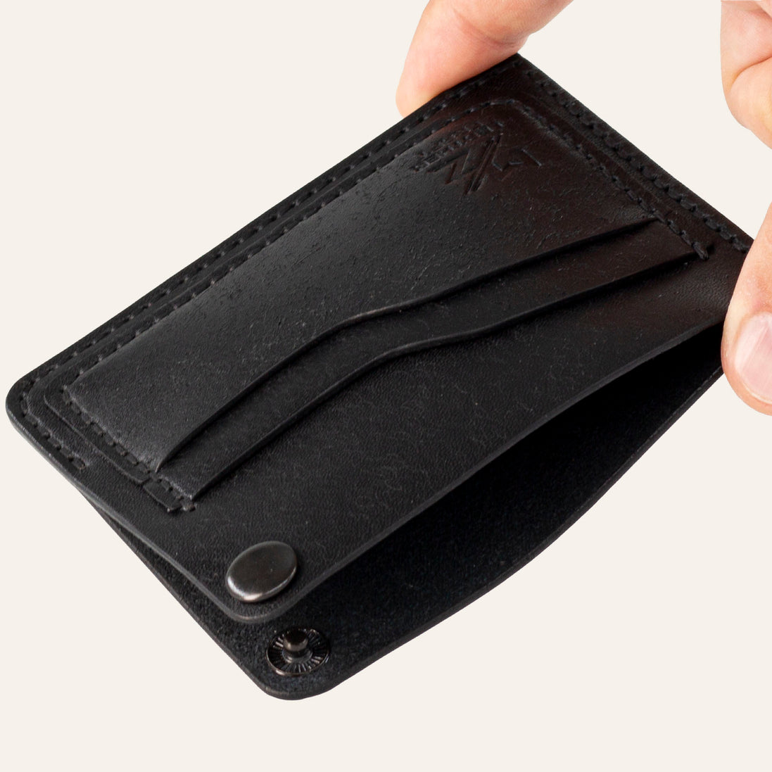 MZ Leather Craft köşe çıtçıtlı ters cüzdan siyah Pueblo deri, el ile tutulan açık köşe çıtçıtlı görünüm, iç bölme ve işlevsel tasarım sunumu | The Inverse Wallet | Corner Snap Edition - Black Pueblo Leather by MZ Leather Craft, open view held by hand showing the unfastened corner snap, inner compartment, and functional design