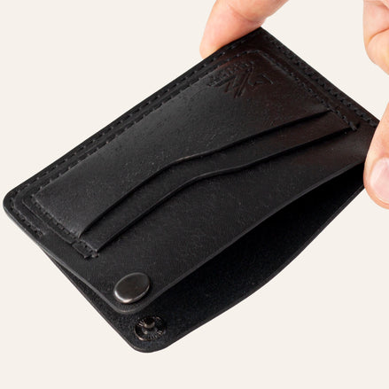 MZ Leather Craft köşe çıtçıtlı ters cüzdan siyah Pueblo deri, el ile tutulan açık köşe çıtçıtlı görünüm, iç bölme ve işlevsel tasarım sunumu | The Inverse Wallet | Corner Snap Edition - Black Pueblo Leather by MZ Leather Craft, open view held by hand showing the unfastened corner snap, inner compartment, and functional design