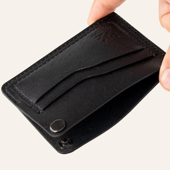 MZ Leather Craft köşe çıtçıtlı ters cüzdan siyah Pueblo deri, el ile tutulan açık köşe çıtçıtlı görünüm, iç bölme ve işlevsel tasarım sunumu | The Inverse Wallet | Corner Snap Edition - Black Pueblo Leather by MZ Leather Craft, open view held by hand showing the unfastened corner snap, inner compartment, and functional design